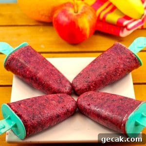 4 fruit popsicles on a white plate with fruit in background