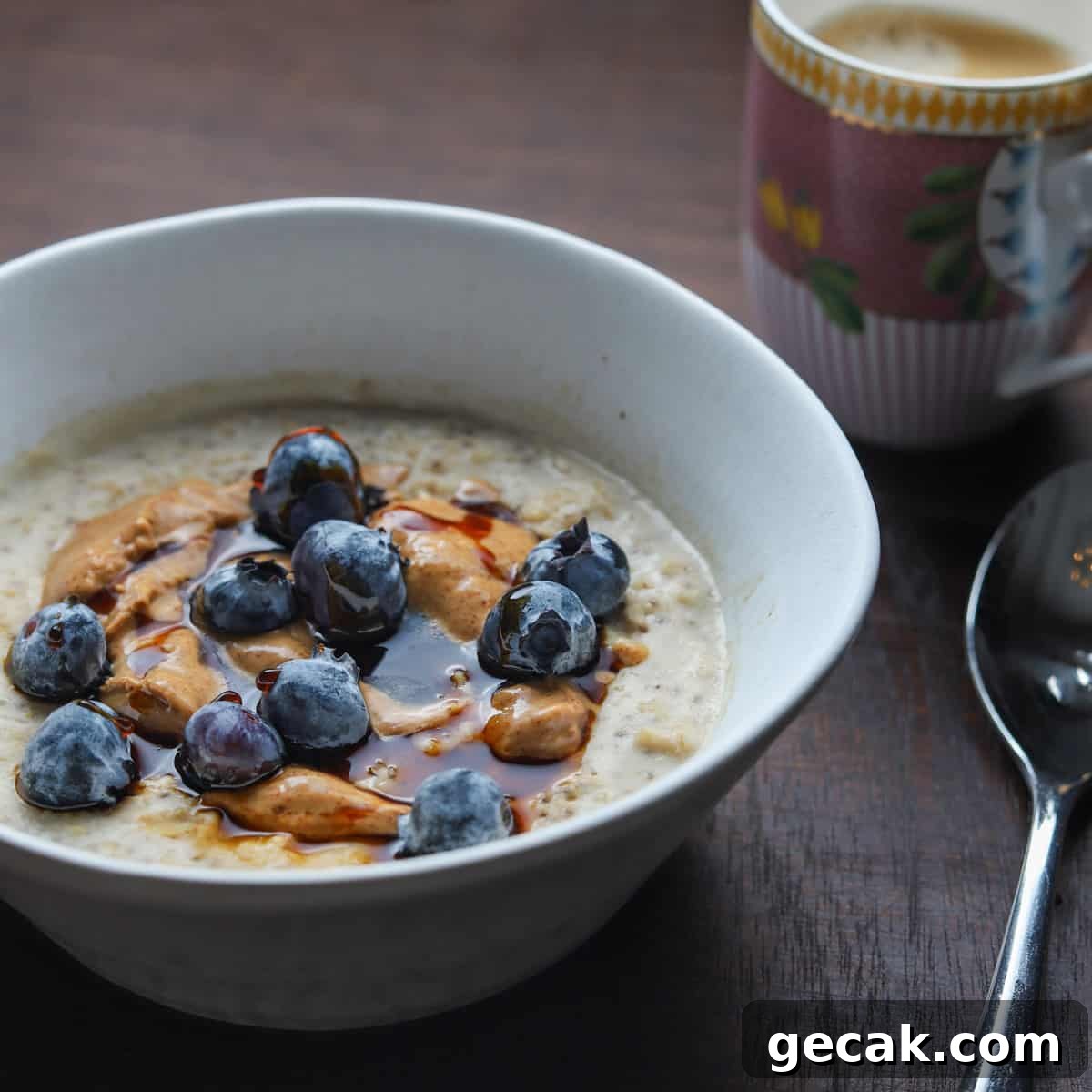 Photo of a bowl of porridge with a coffee and spoon on a wooden table top.