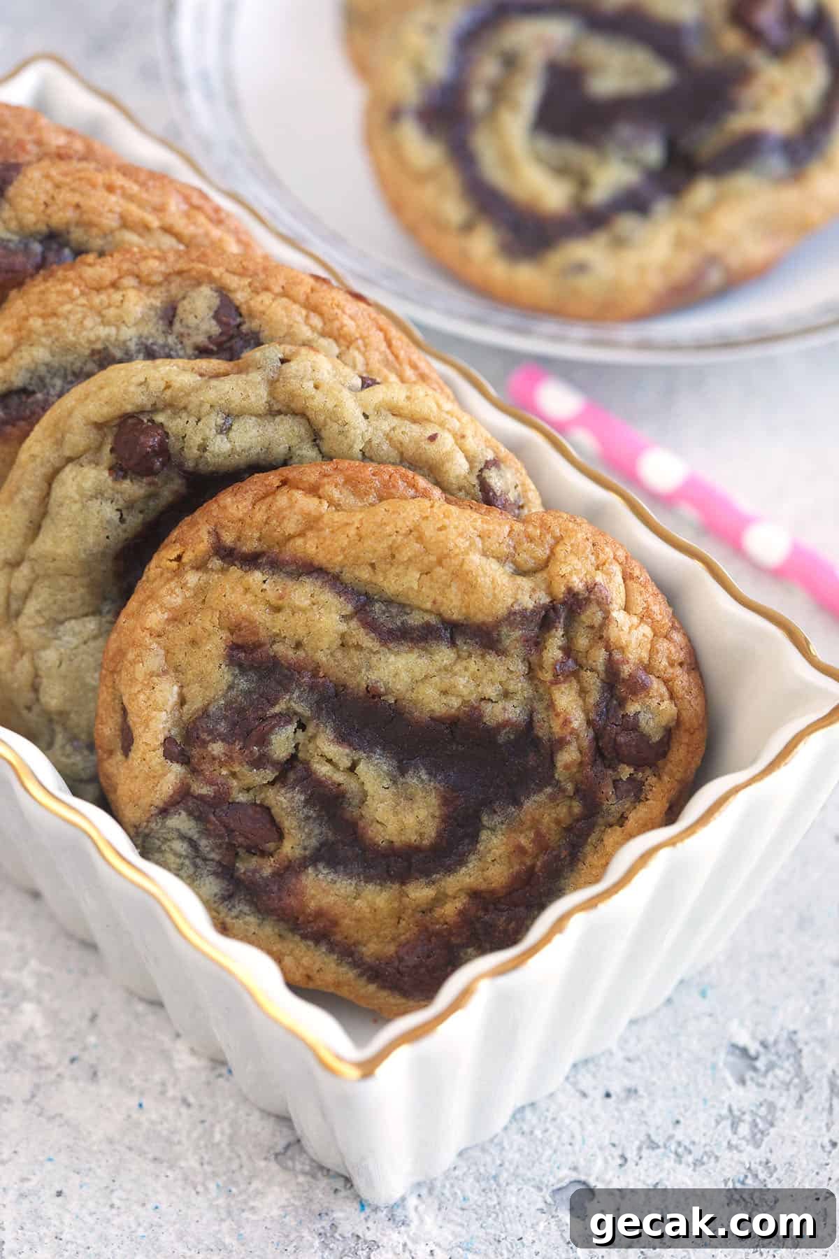 Brookie cookies in a white ceramic loaf pan with a pink polka dot straw on a gray background.