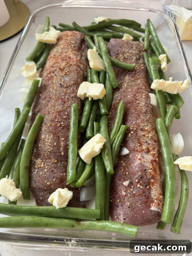 Butter and green beans have been added to the tenderloins in the baking dish
