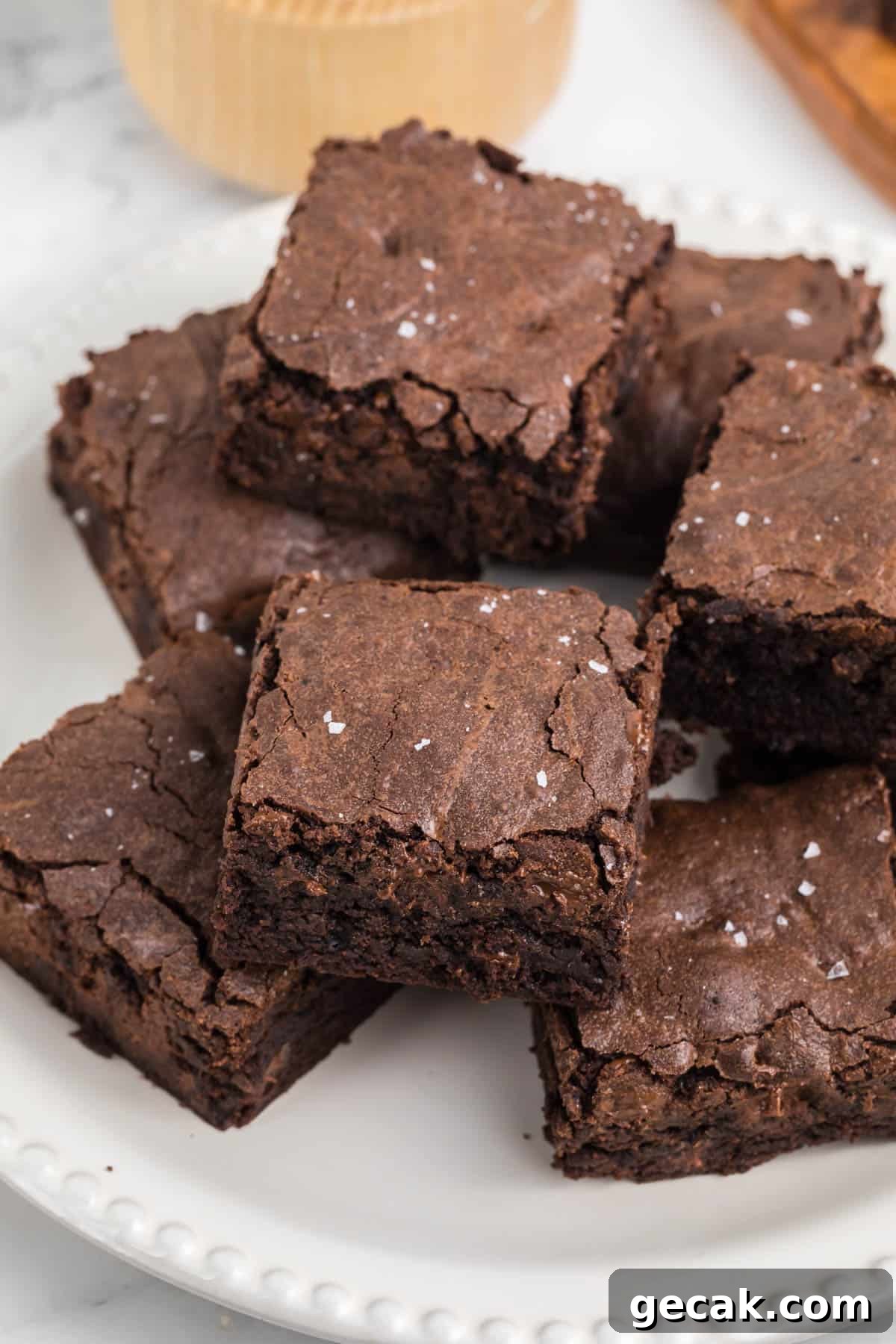 A plate of six chocolate, homemade brownies topped with a sprinkle of coarse salt.