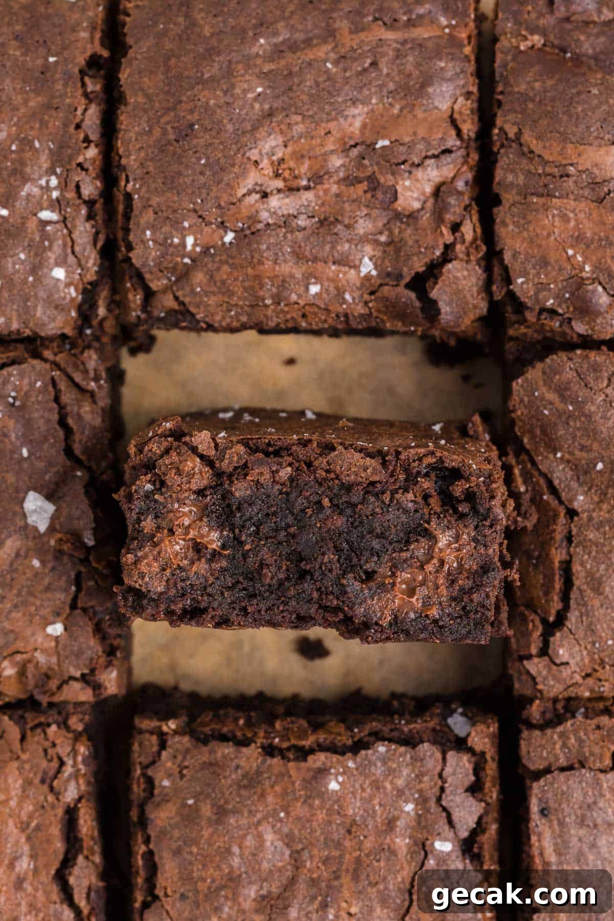A close-up of homemade brownies cut into squares, with one brownie piece lifted to show its moist, dense interior.