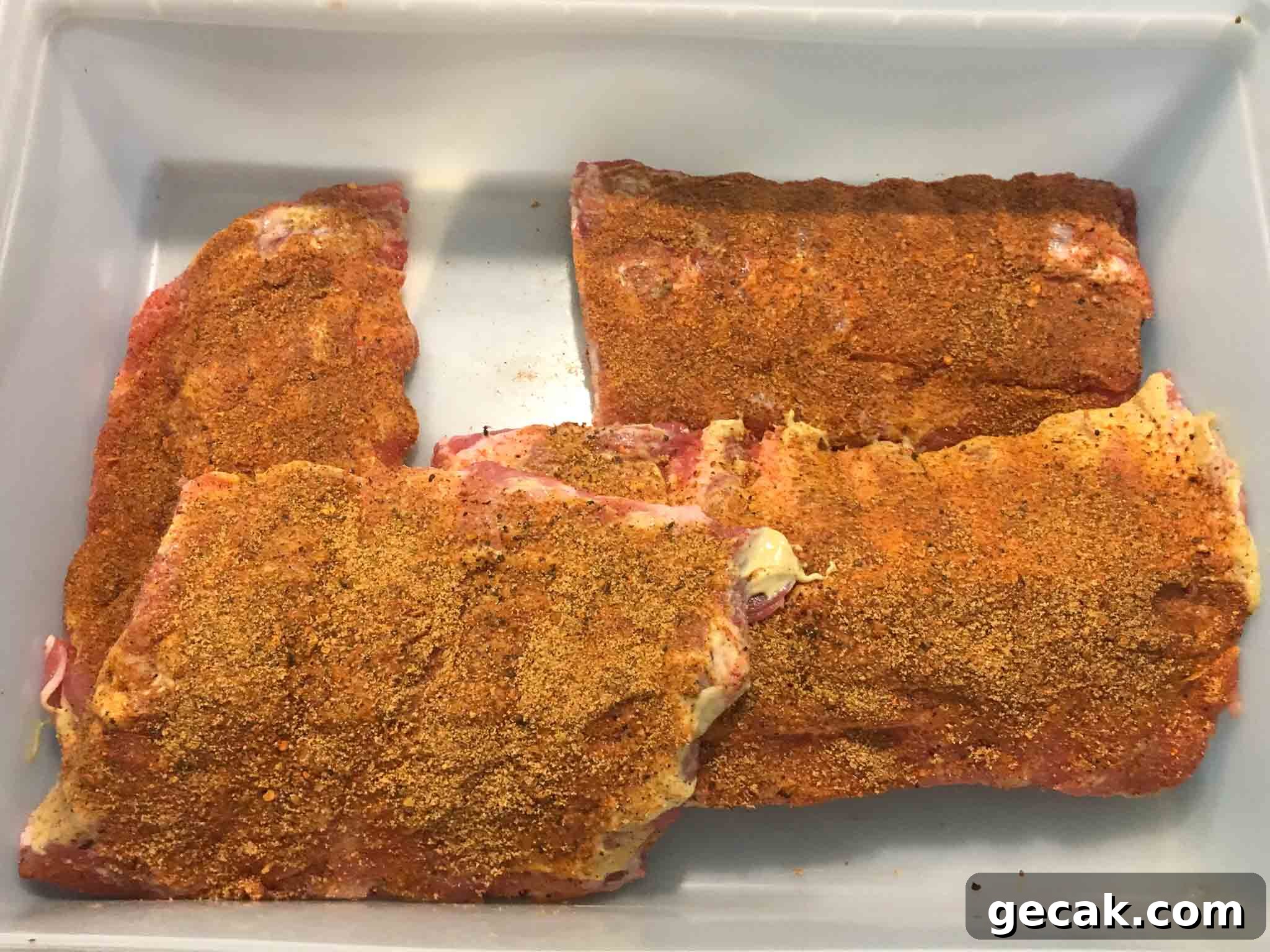 racks of ribs covered in dry rub in white container overhead shot