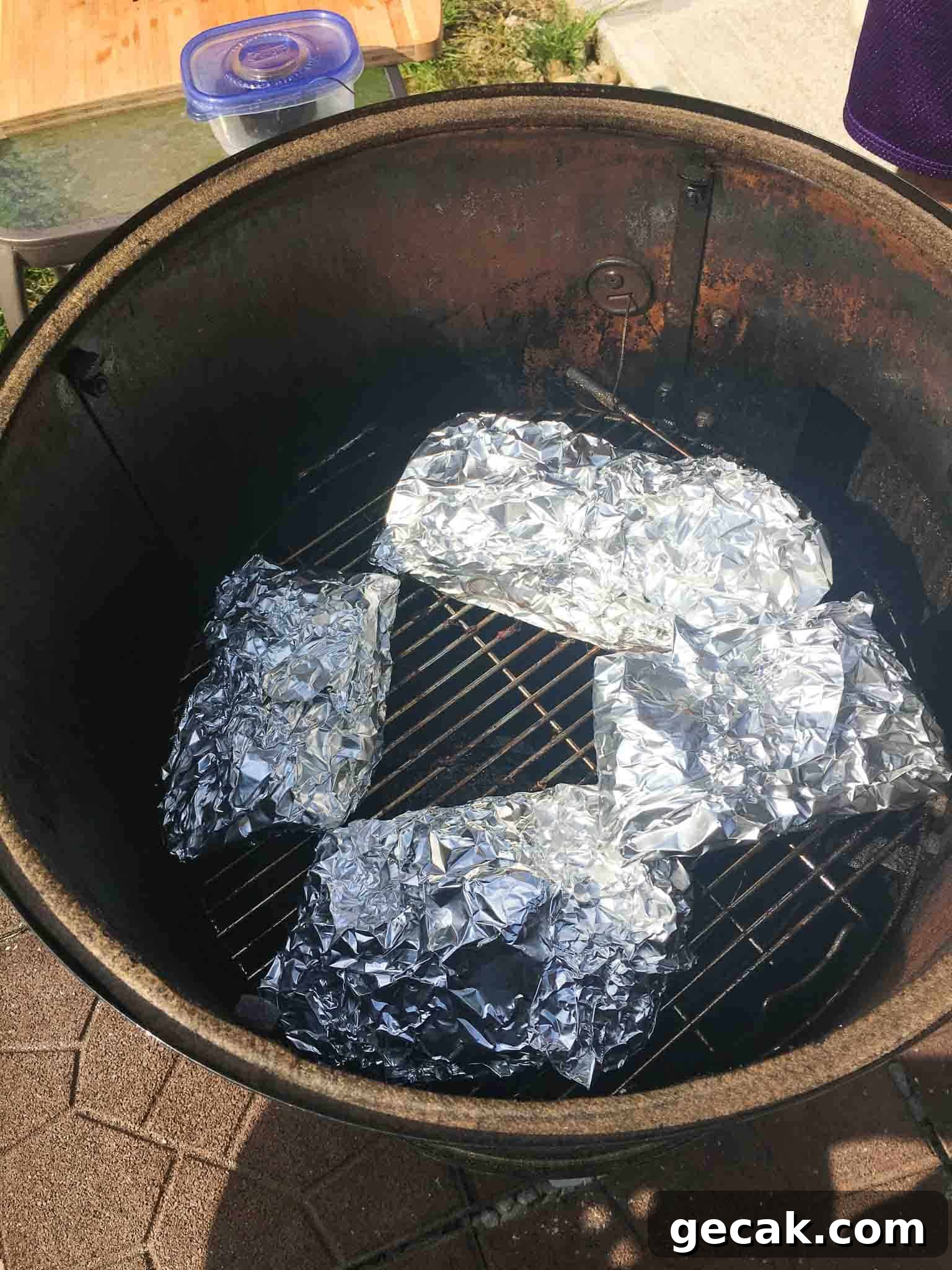 ribs wrapped in foil inside of weber grill overhead shot