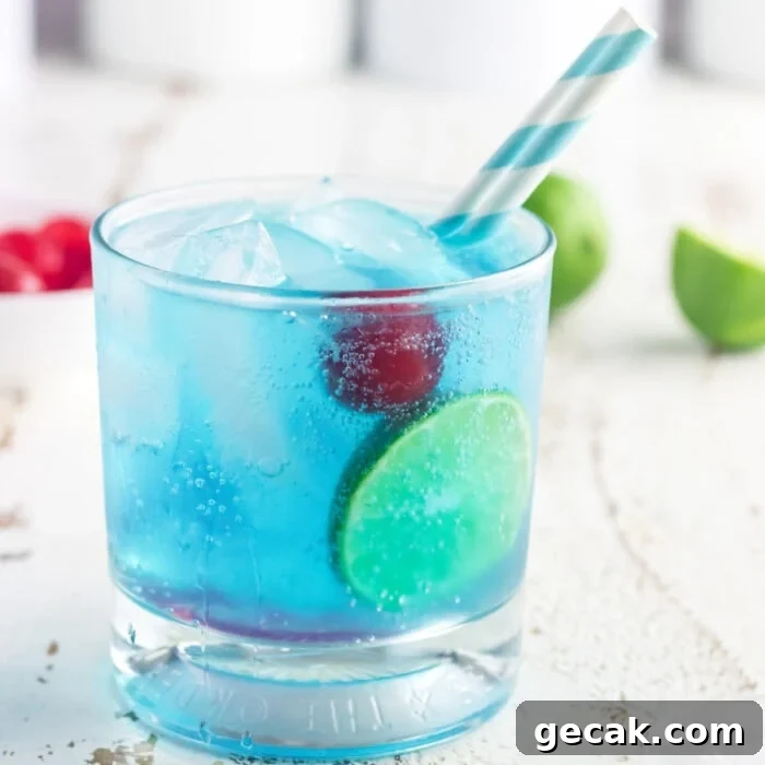 Closeup of a glass of gin and tonic with a cherry in it.