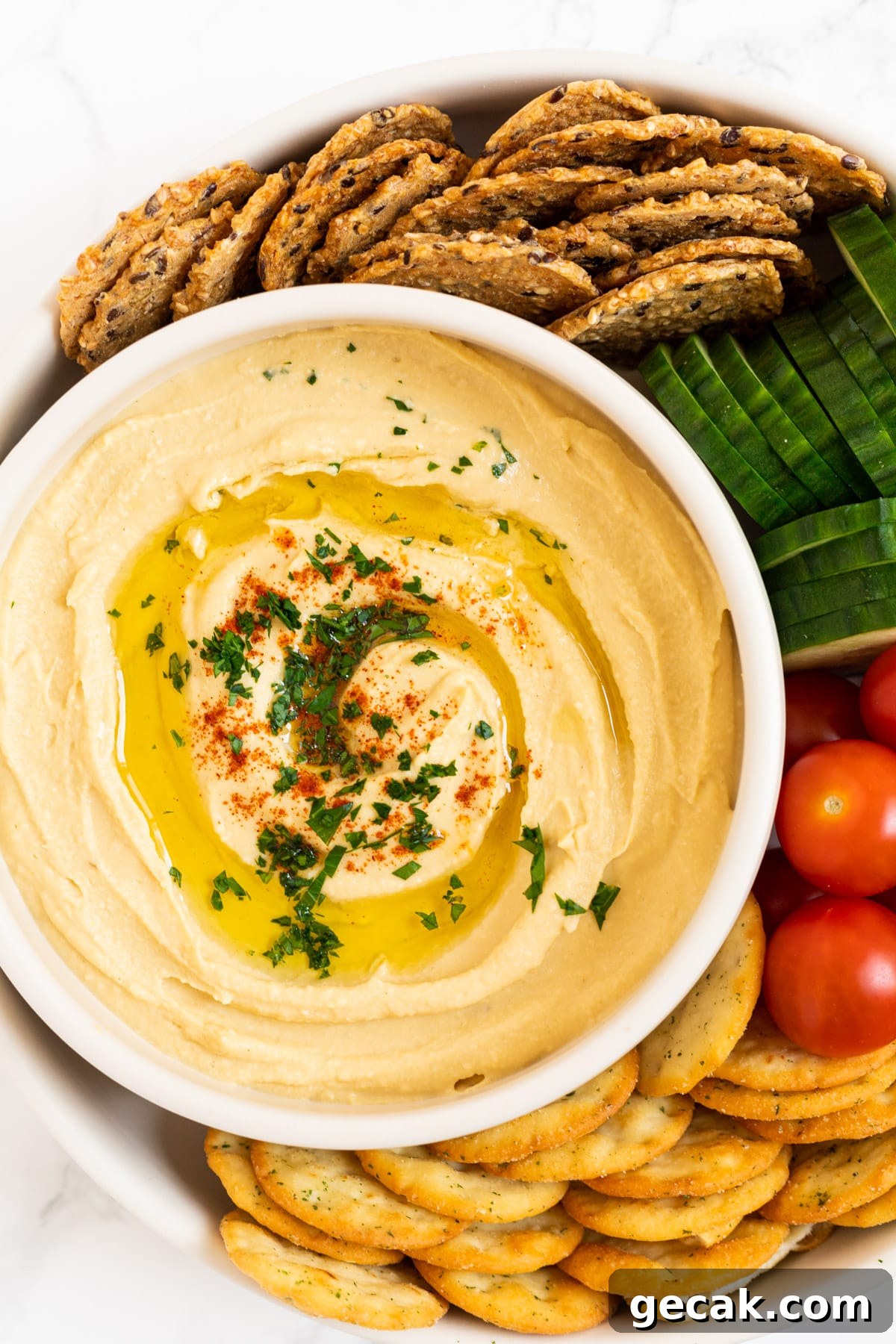 Creamy Chickpea Hummus Recipe: Classic Homemade Dip 2 A top down view of a bowl of chickpea hummus surrounded by crackers and veggies.