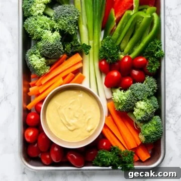a top down view of a platter of veggies with a bowl of curry dip on it.