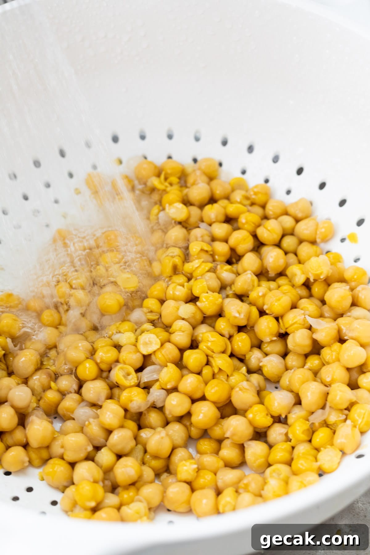 Creamy Chickpea Hummus Recipe: Classic Homemade Dip 4 Chickpeas in a colander rinsing cooling under running water.