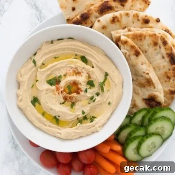 a bowl of chana dal hummus surrounded by veggies and pita
