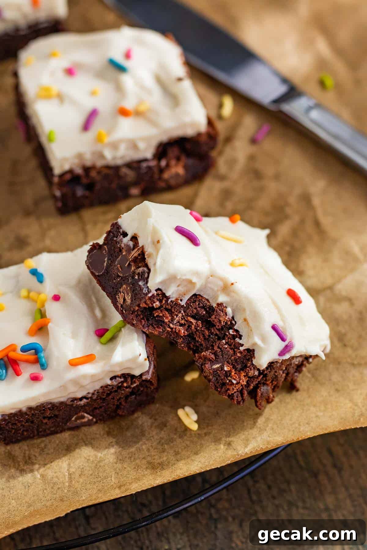 brownie with cream cheese frosting with a bite out of the corner and sitting propped up against another brownie