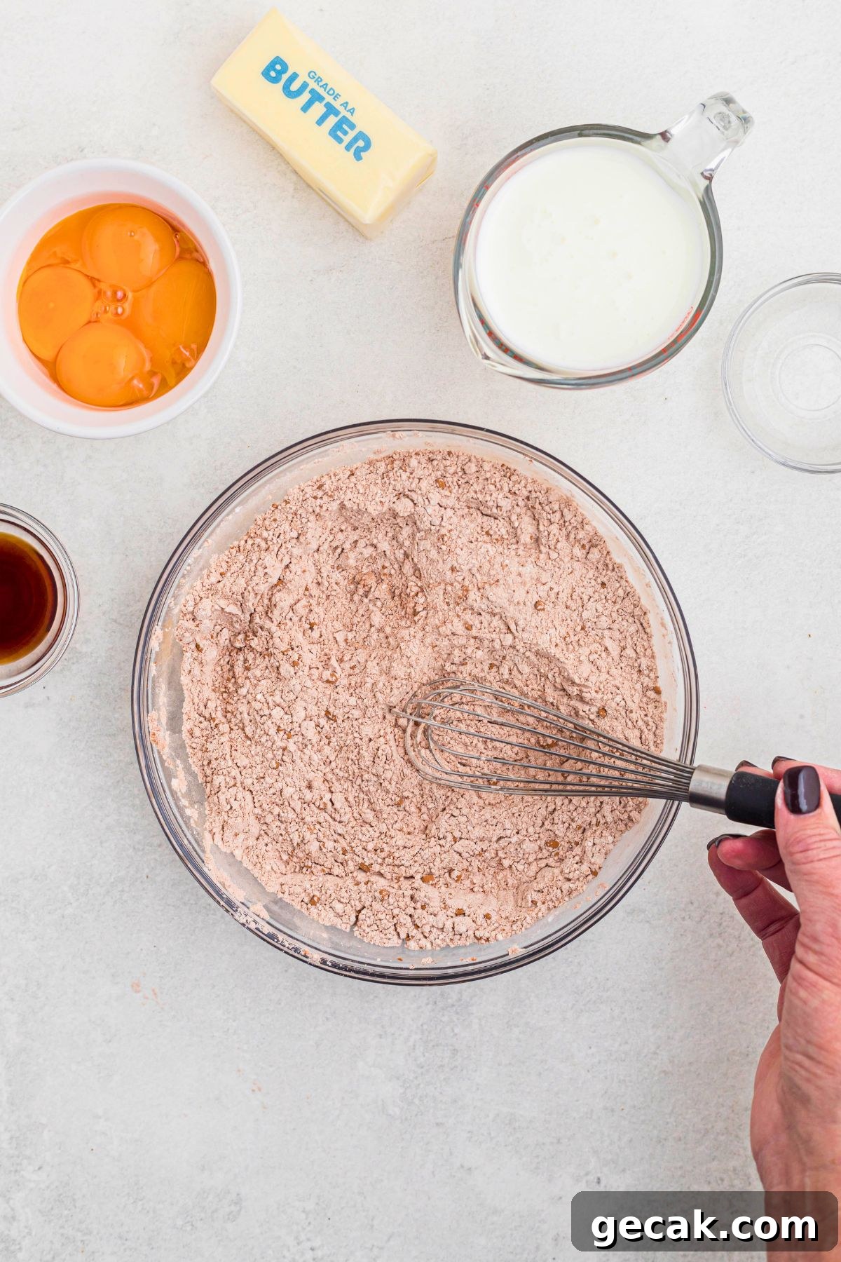 Dry ingredients for red velvet cupcakes being stirred together in a clear glass bowl.