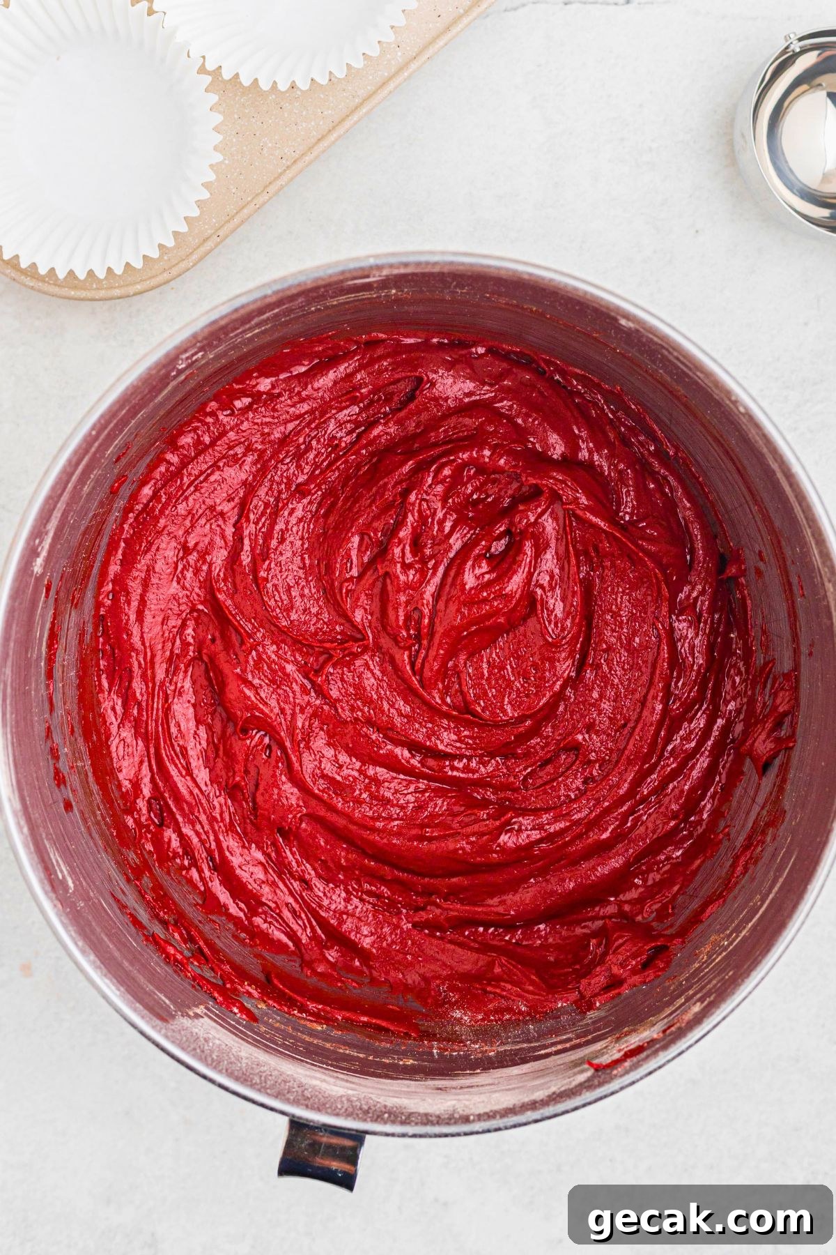 Red velvet cupcake batter mixed in a silver bowl.