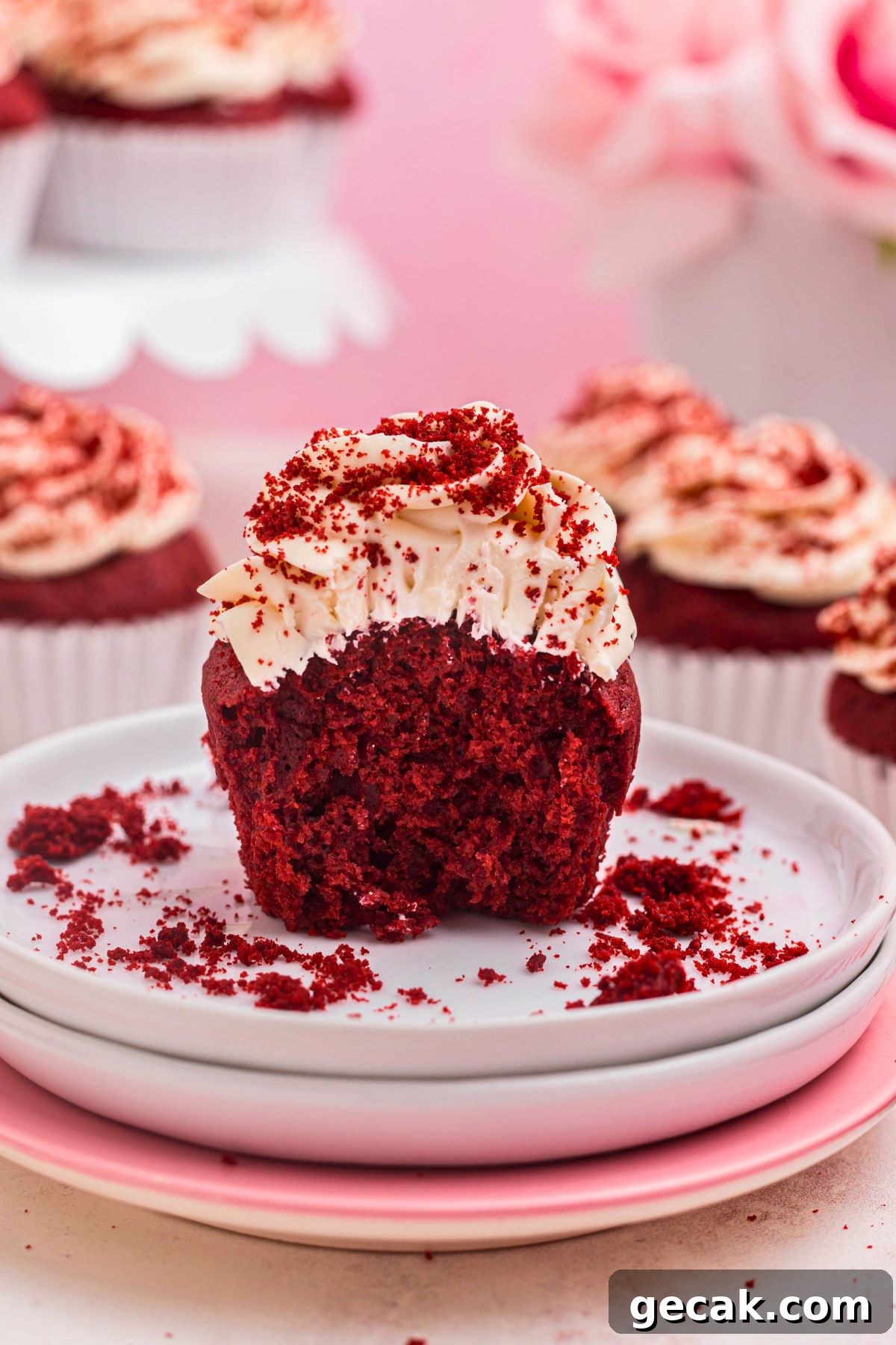 Bright red cupcakes with a small part cut aside showing the texture.