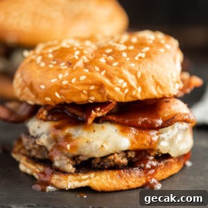 A hamburger with bacon and cheese on a black surface.