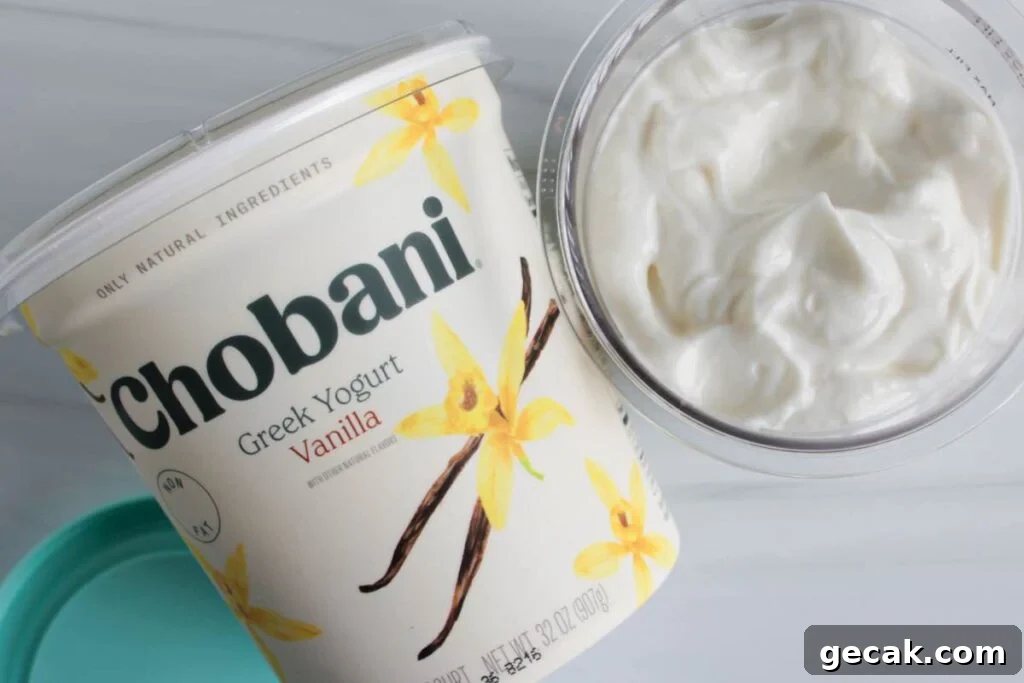 A large container of chobani greek yogurt for making ninja creami frozen yogurt on a countertop with a ninja creami pint container full of yogurt.