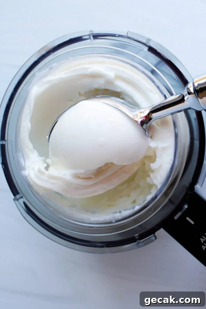 A close up shot of vanilla greek yogurt frozen yogurt in the Ninja Creami machine being scooped.