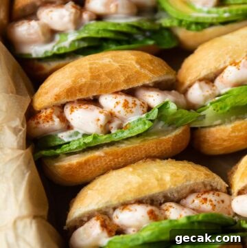 close up shot of prawn cocktail sandwiches lined up in dish with brown parchment paper