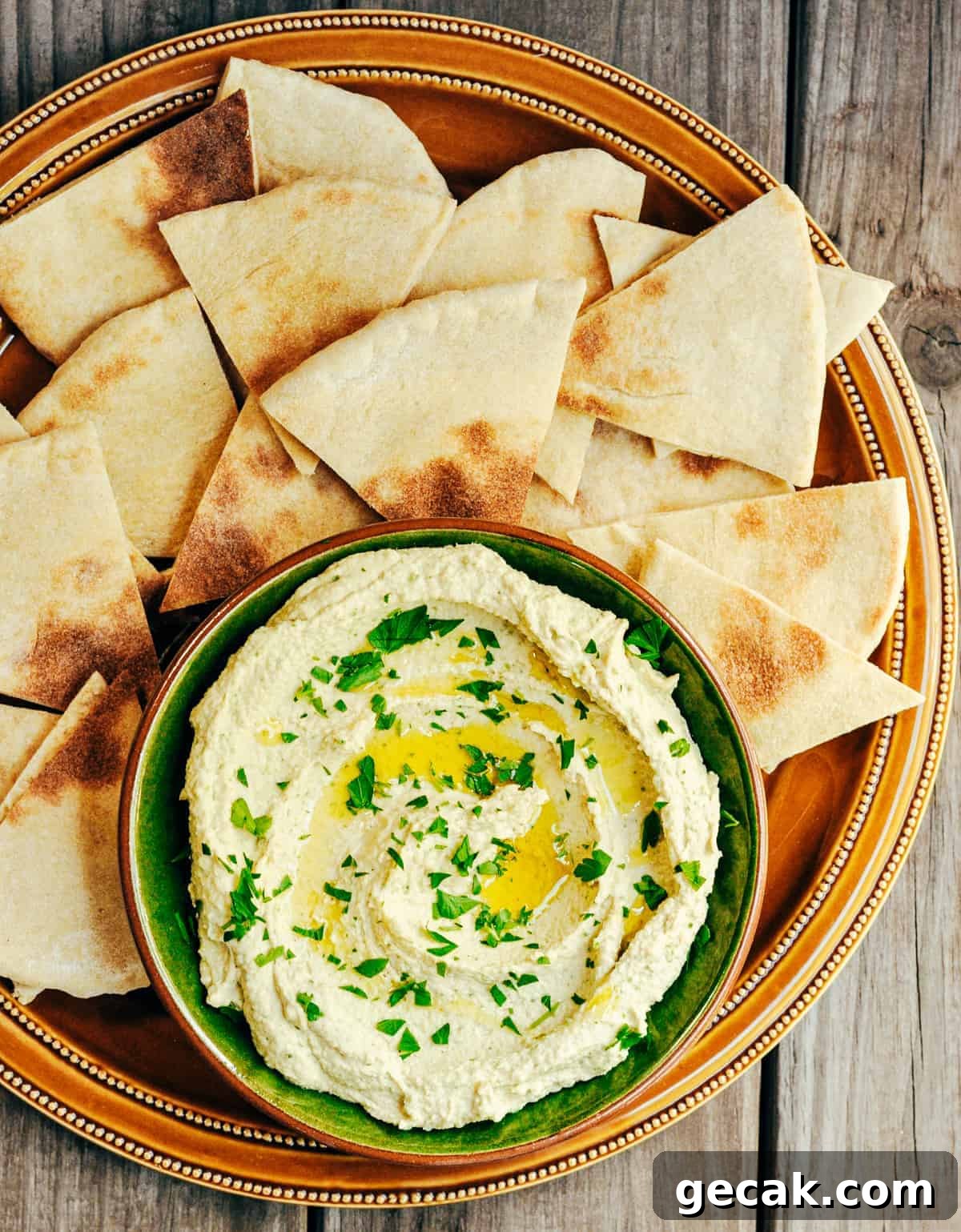 White Bean Hummus served in a green ceramic bowl with pita bread for dipping and photographed from the top.