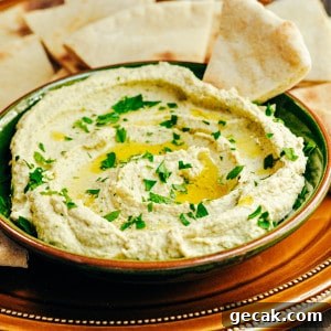 White Bean Hummus served in a green ceramic bowl with pita bread for dipping.