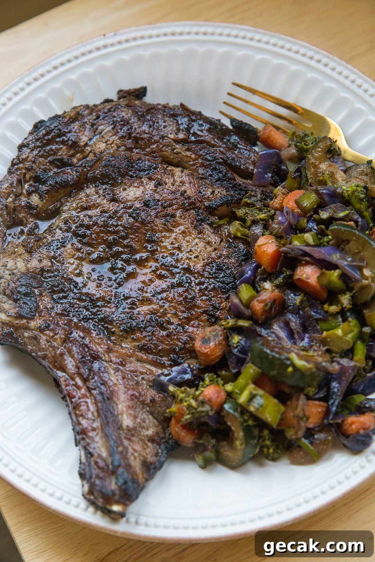 How to Grill the Perfect Steak Every Time 3 Grilled steak on a plate next to roasted vegetables, ready to ear.