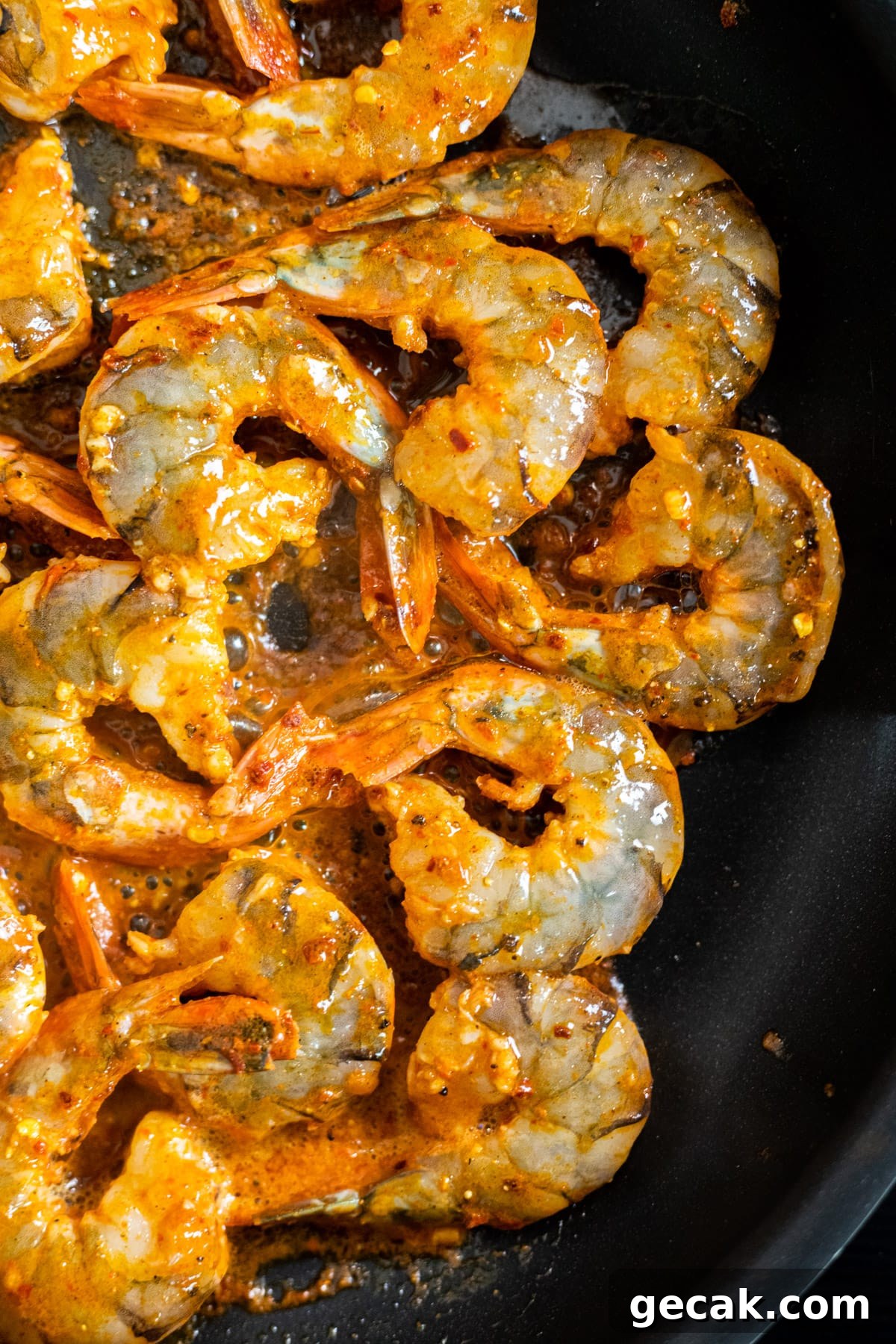 Chili seasoned shrimp cooking in a skillet.