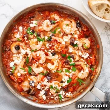 A top down view of Greek shrimp with tomatoes and feta cheese in a skillet.