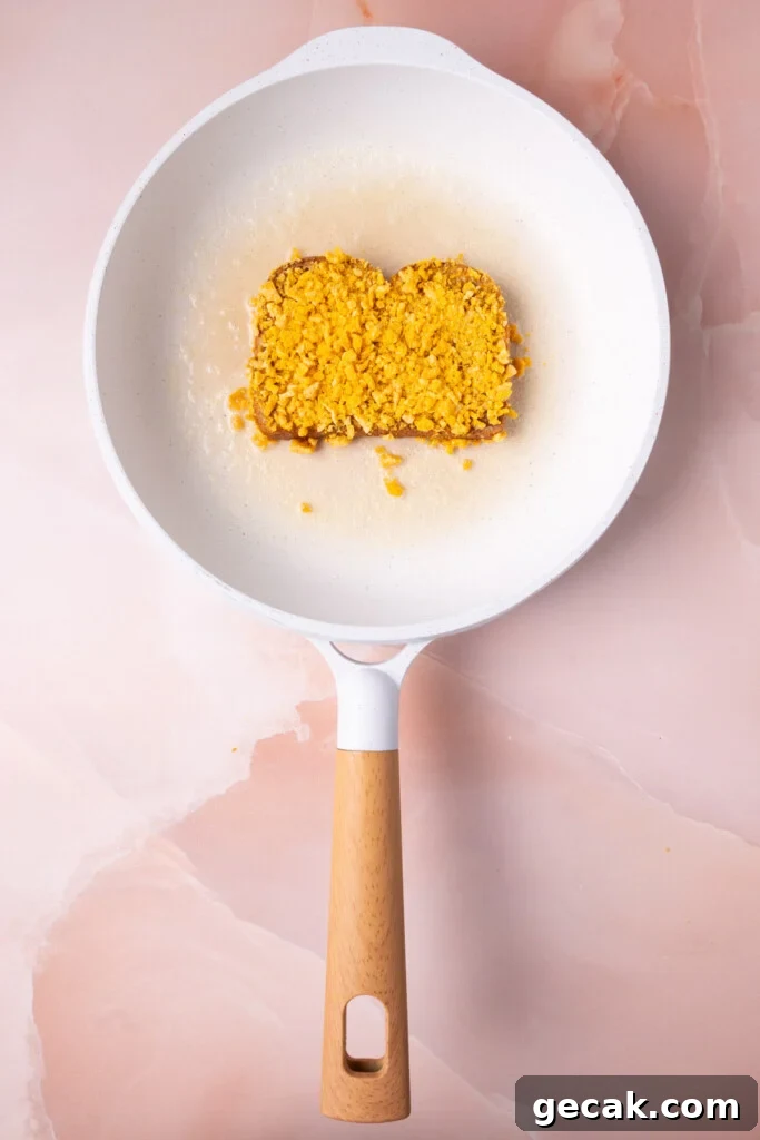 25-Minute Crunchy Cap'n Crunch French Toast Recipe 13 Placing Captain Crunch coated French toast into hot butter in a pan to fry.