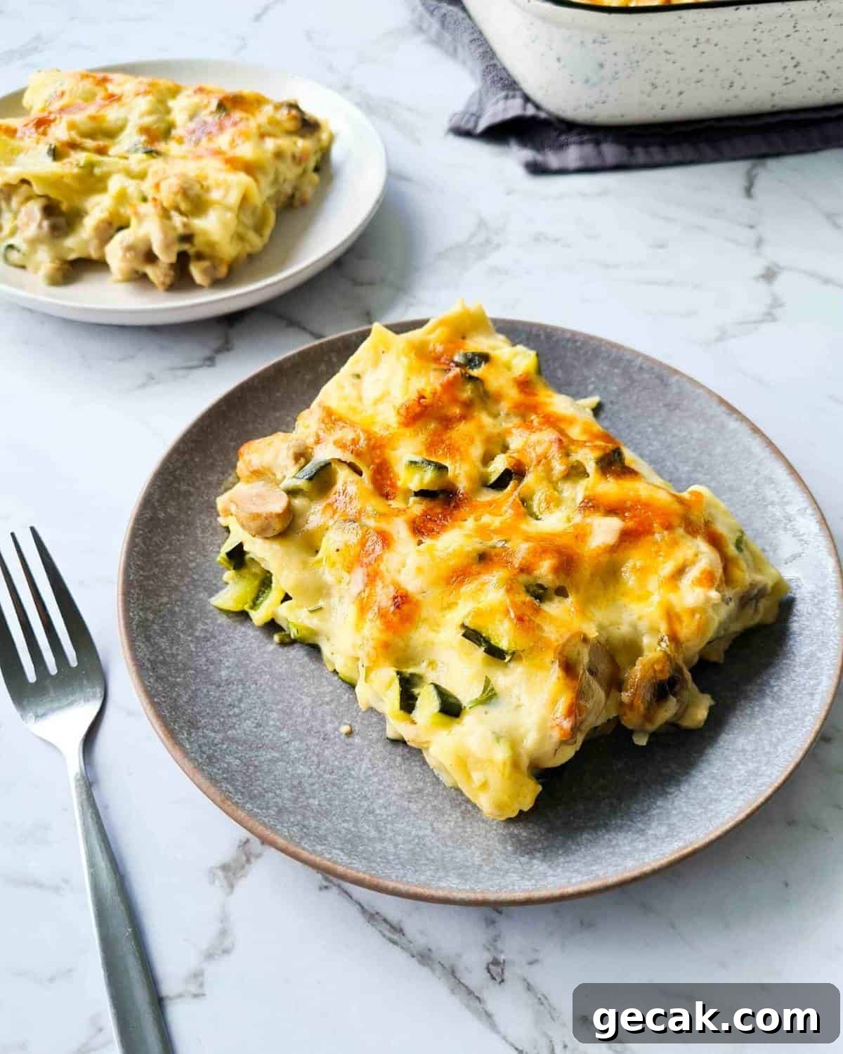 A slice of cheesy creamy chicken lasagna on a grey plate