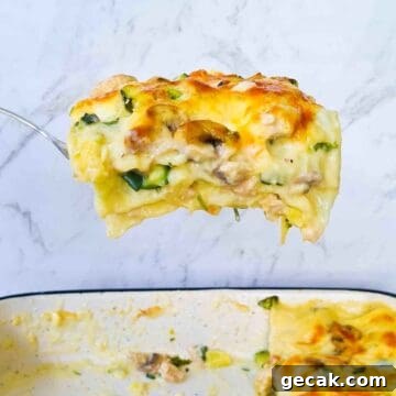 A slice of creamy chicken lasagna being scooped out of a baking tray
