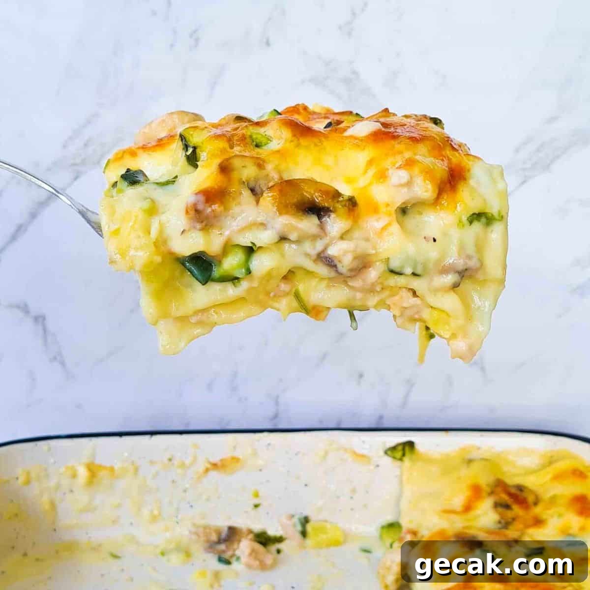 Side view of slice of white lasagna being scooped out of baking dish