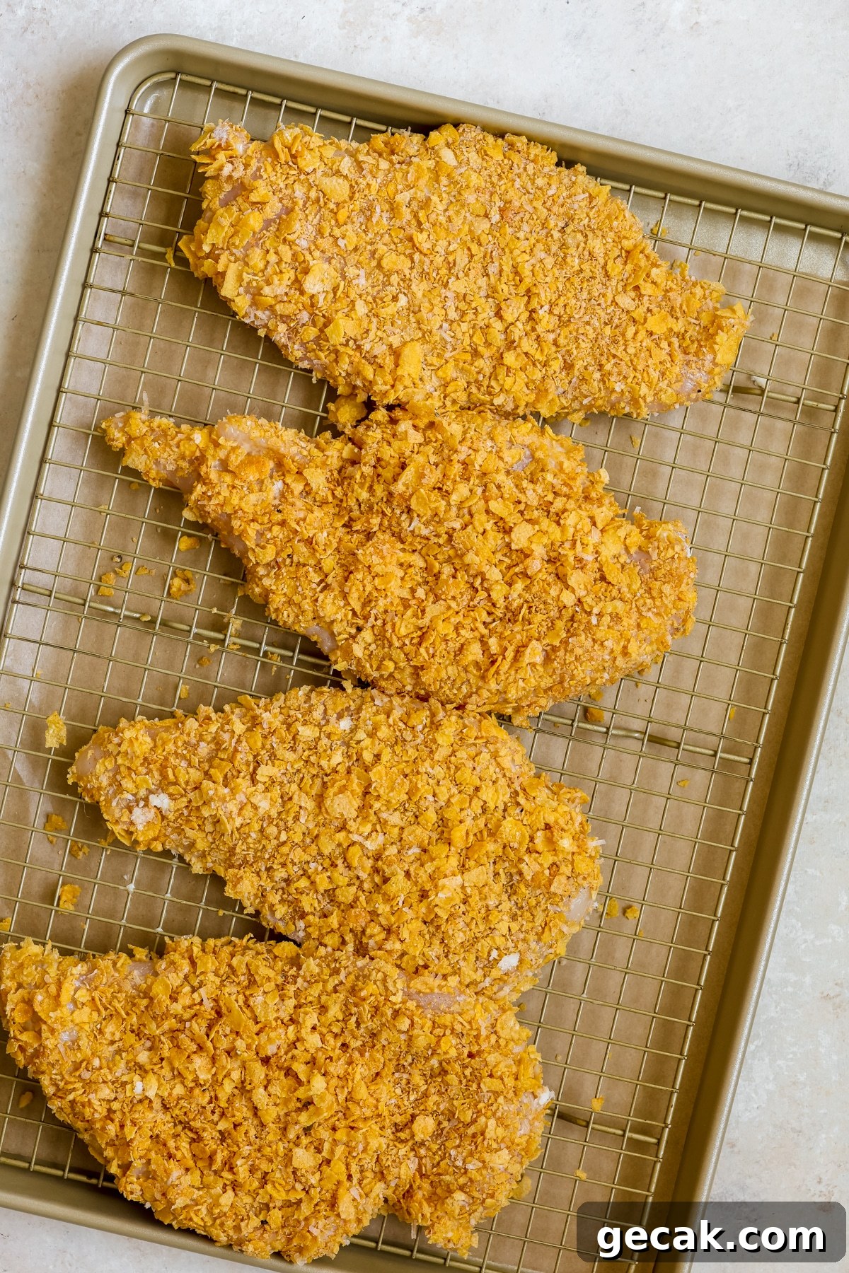 chicken coated in cornflakes on a baking sheet. 
