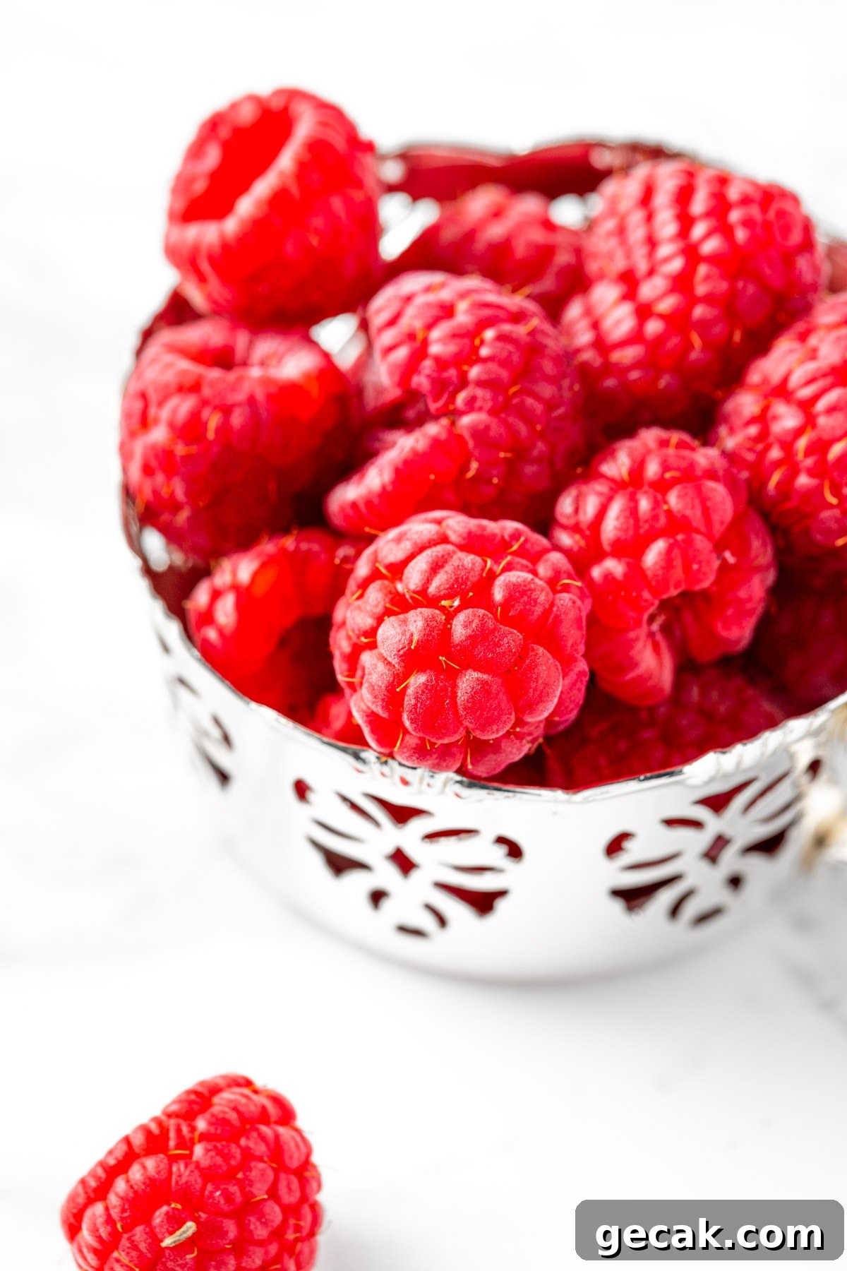 Homemade Raspberry Simple Syrup Recipe for Cocktails & Desserts 3 A small metal cup filled with fresh raspberries.