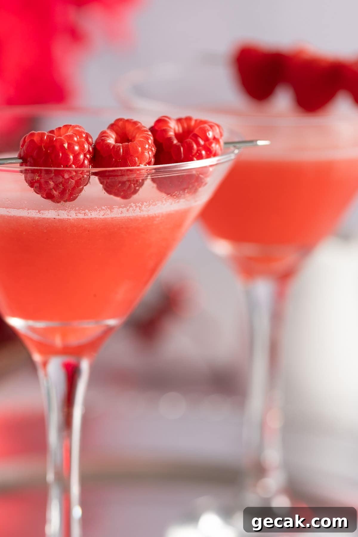 Homemade Raspberry Simple Syrup Recipe for Cocktails & Desserts 4 Up close view of the edge of a martini glass, garnished with raspberries.