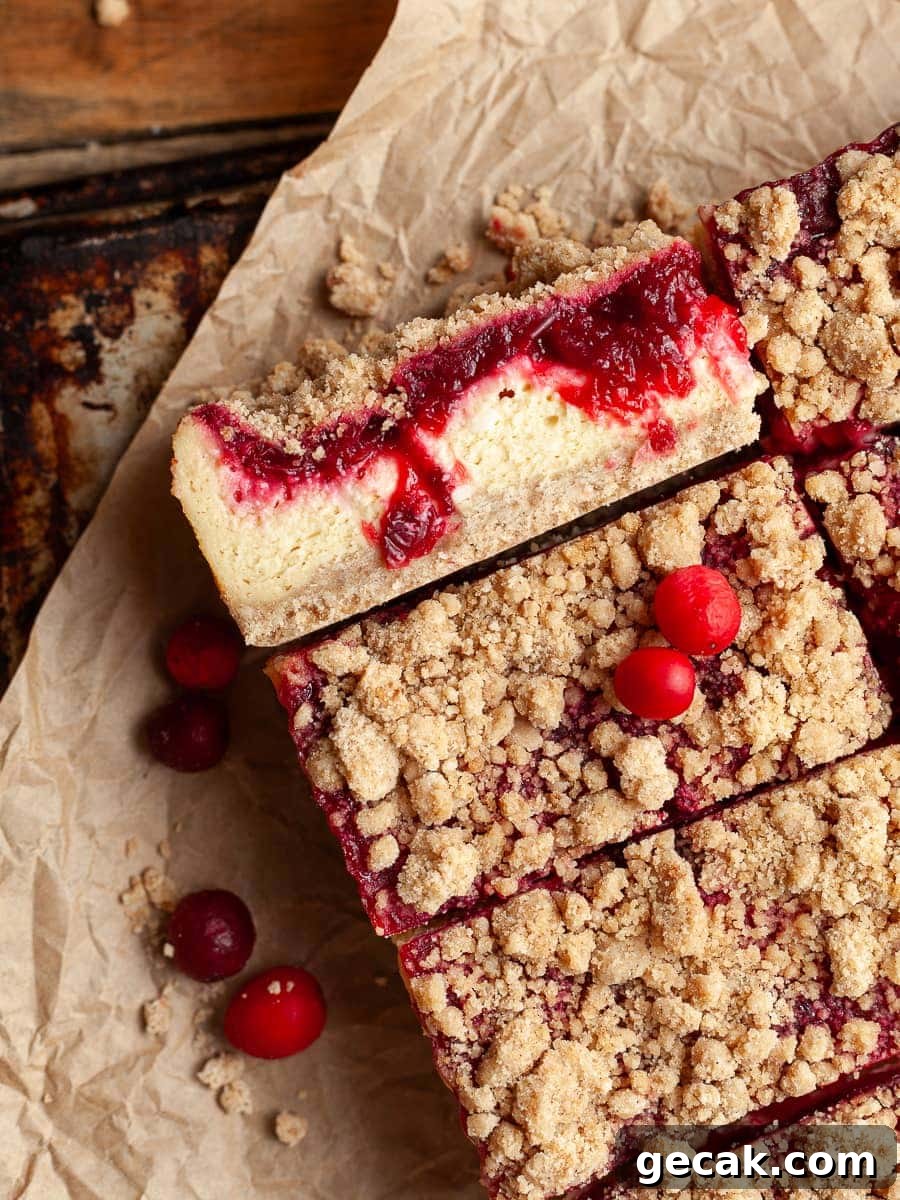 Sliced gluten free cranberry cheesecake bars topped with cranberry sauce and streusel