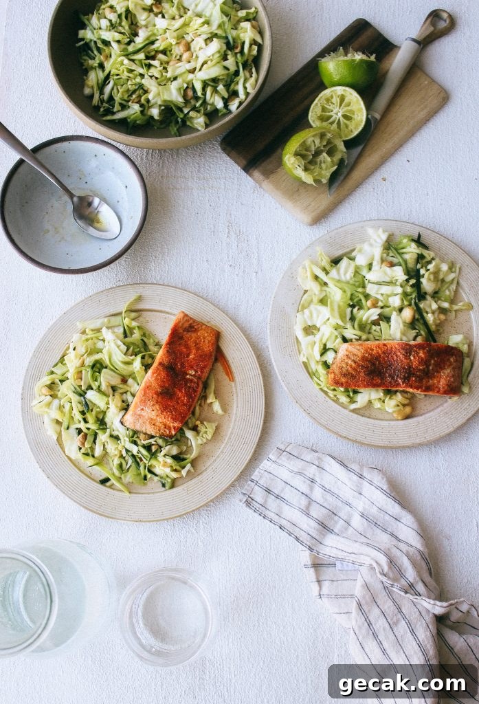 cabbage and cucumber salad with salmon on plates and limes on wood cutting board