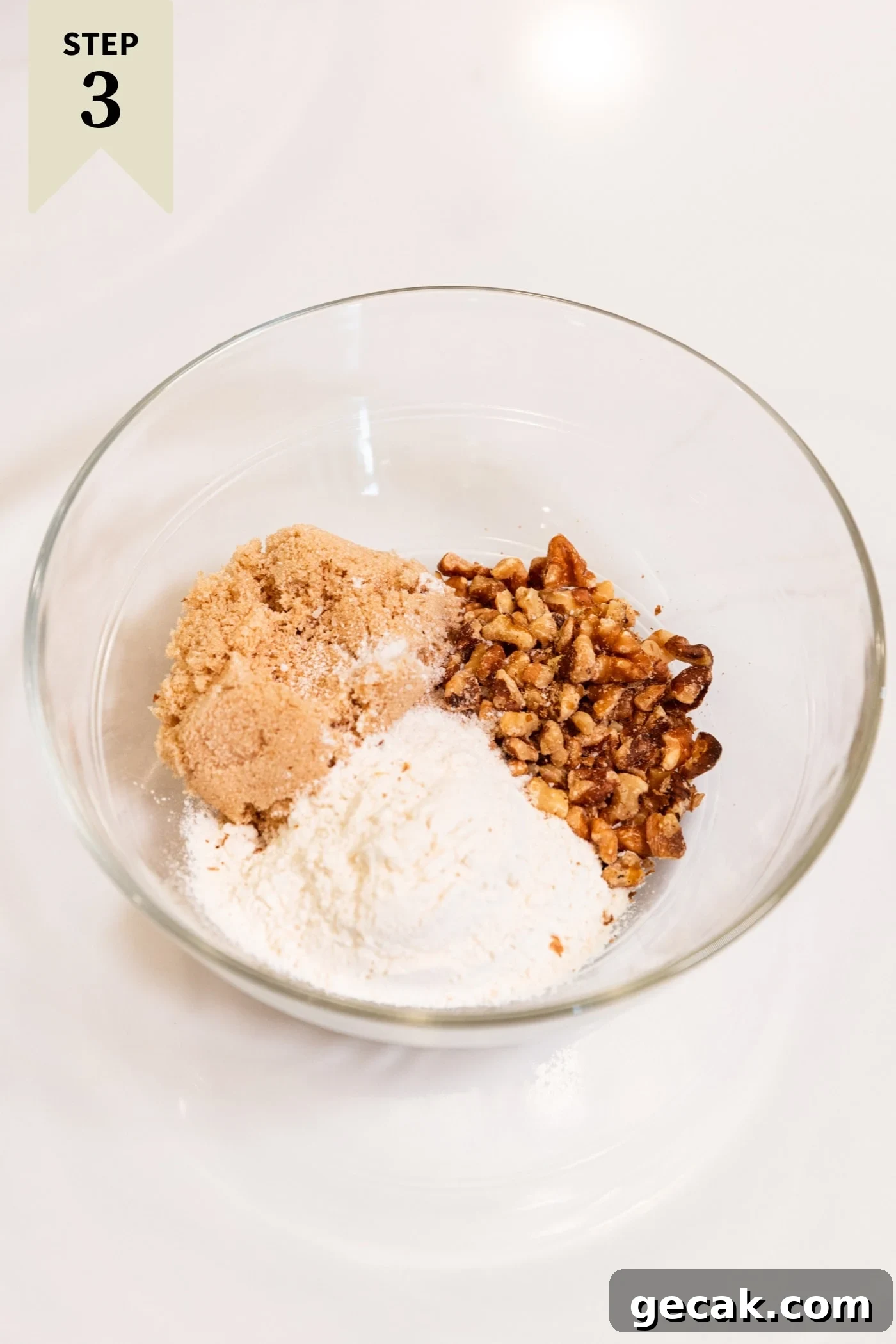 Glass bowl filled with ingredients needed for a streusel topping including brown sugar, white sugar, and nuts.