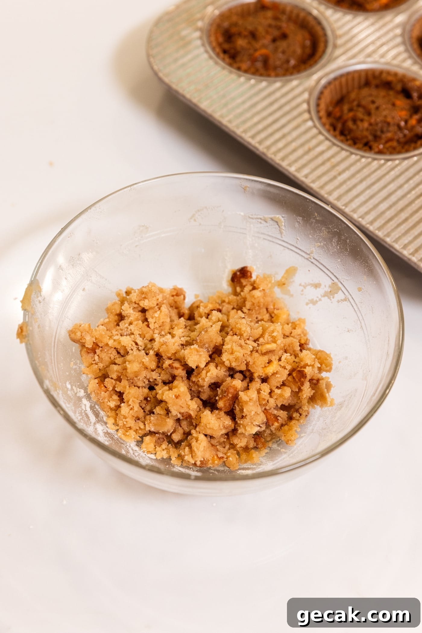 Glass bowl filled with streusel topping after being mixed together with nuts showing.