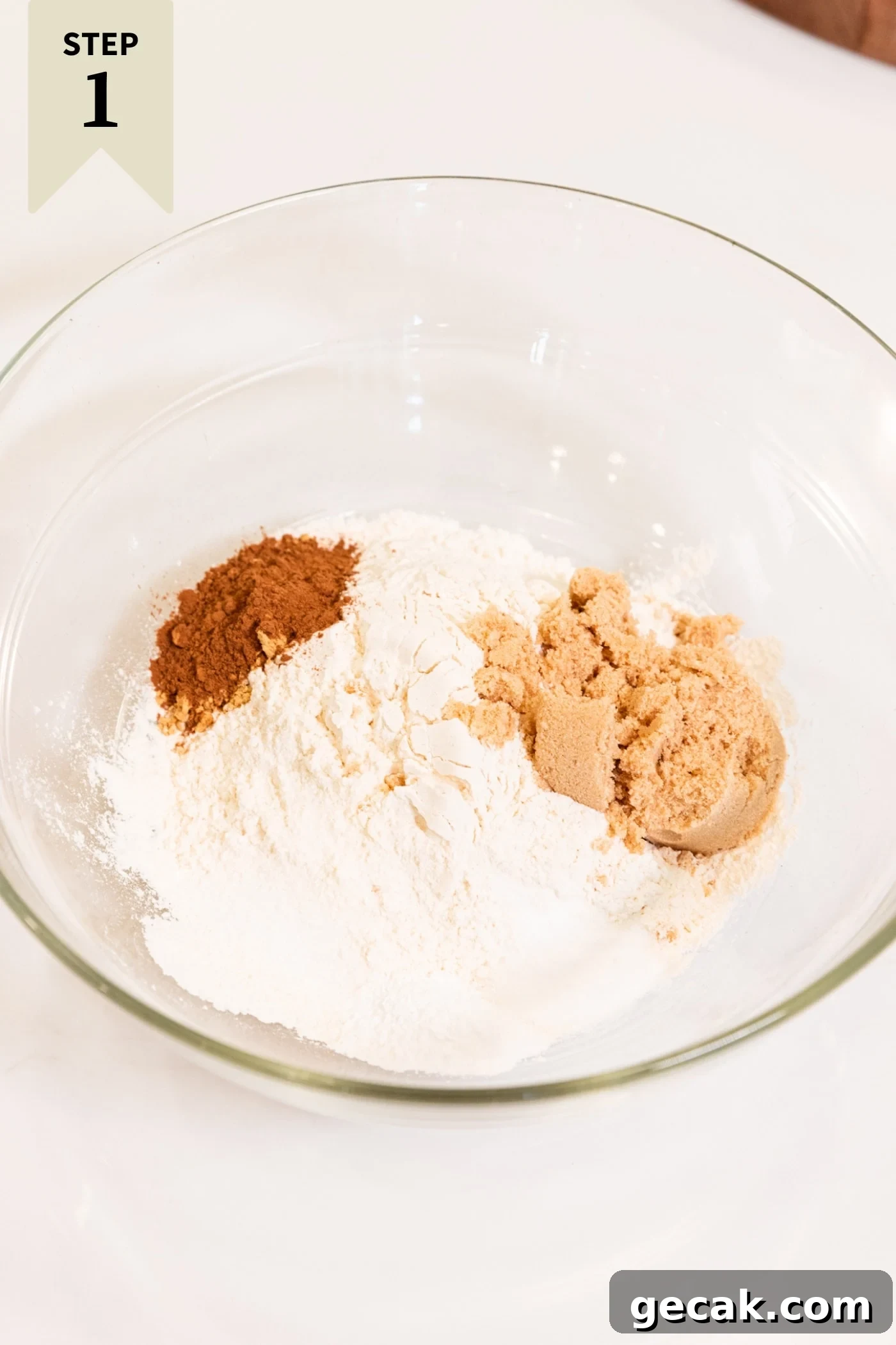 Glass bowl filled with flour, sugar, brown sugar, and spices before being mixed together.