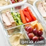 A glass container with chicken, pepper, carrots, cucumber, and more meal prepped for lunch.