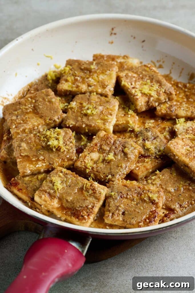 Crispy tofu topped with lemon zest in a skillet.