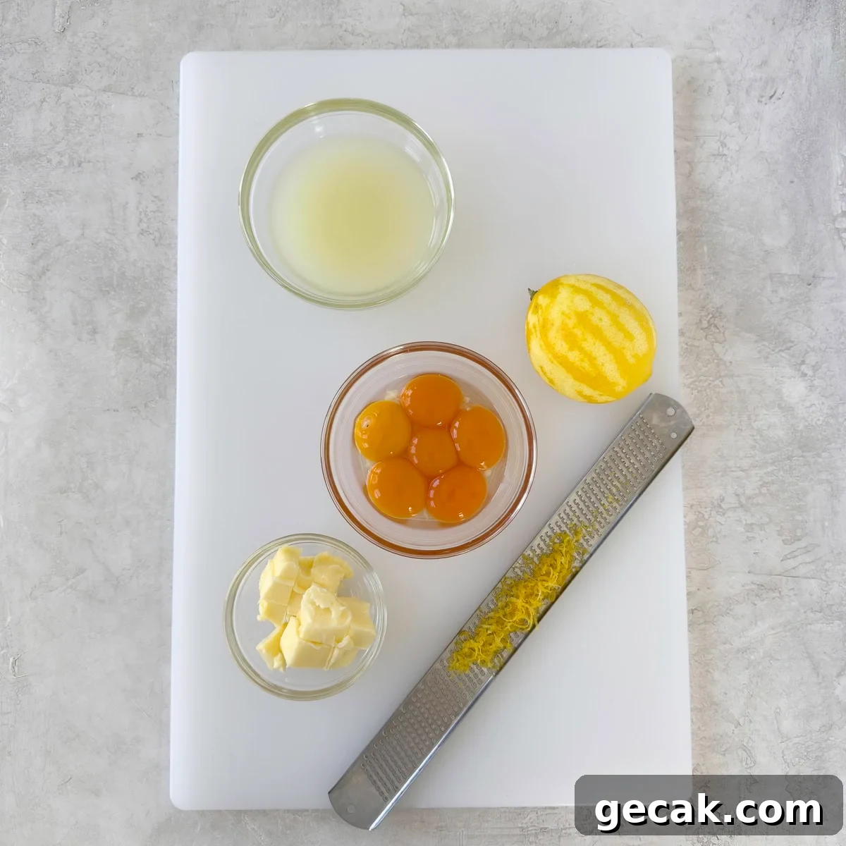 Prep work for lemon curd on a cutting board with lemon juice, butter, and egg yolks. 