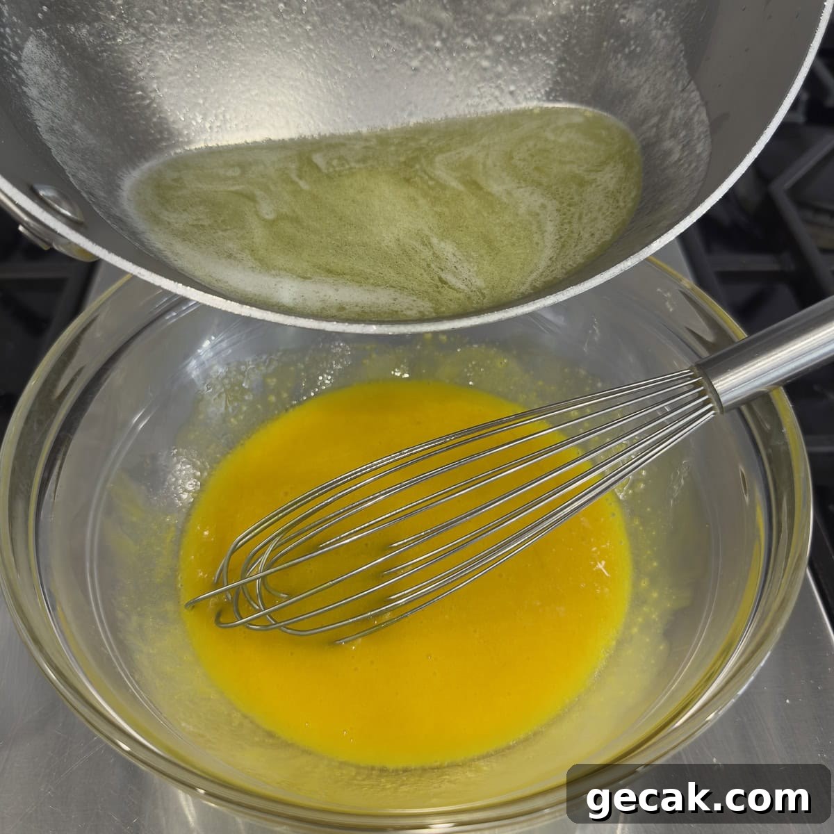 Bright yellow egg yolks in a bowl with a steel whisk