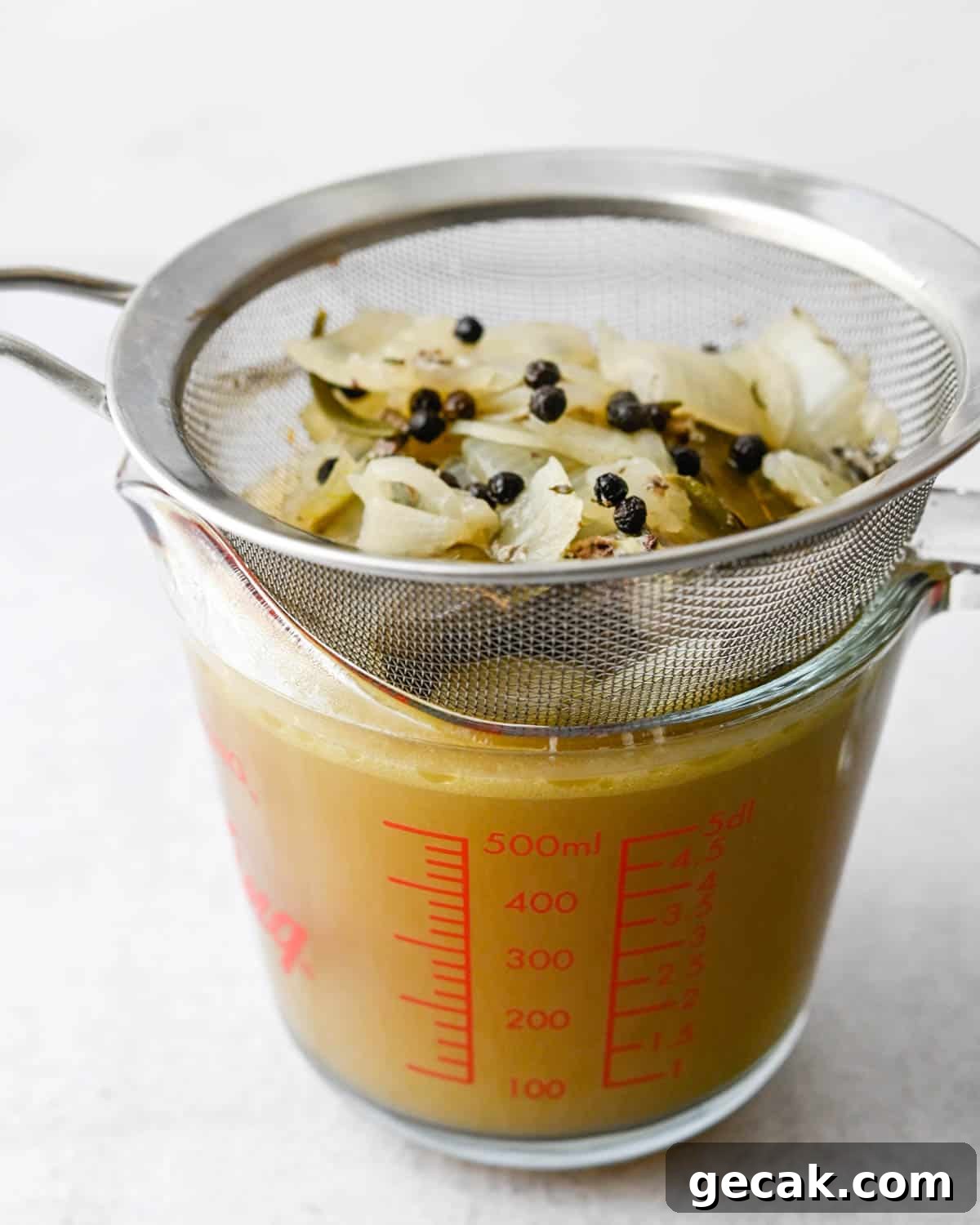 straining the vegetables and seasonings from the turkey stock.
