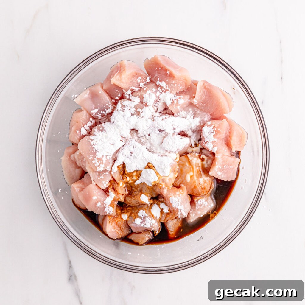 cubed raw chicken in glass bowl with flour and seasoning