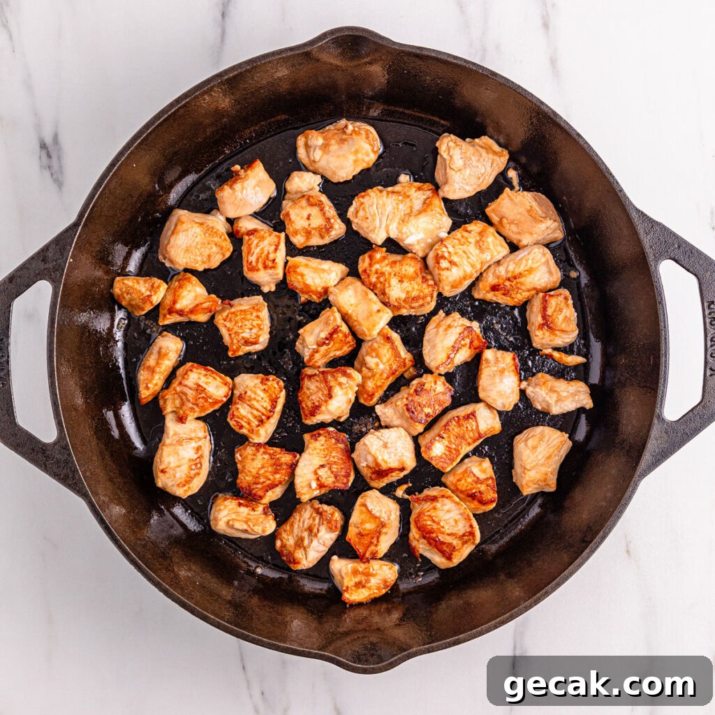 browning cubed chicken in cast iron skillet for black pepper chicken