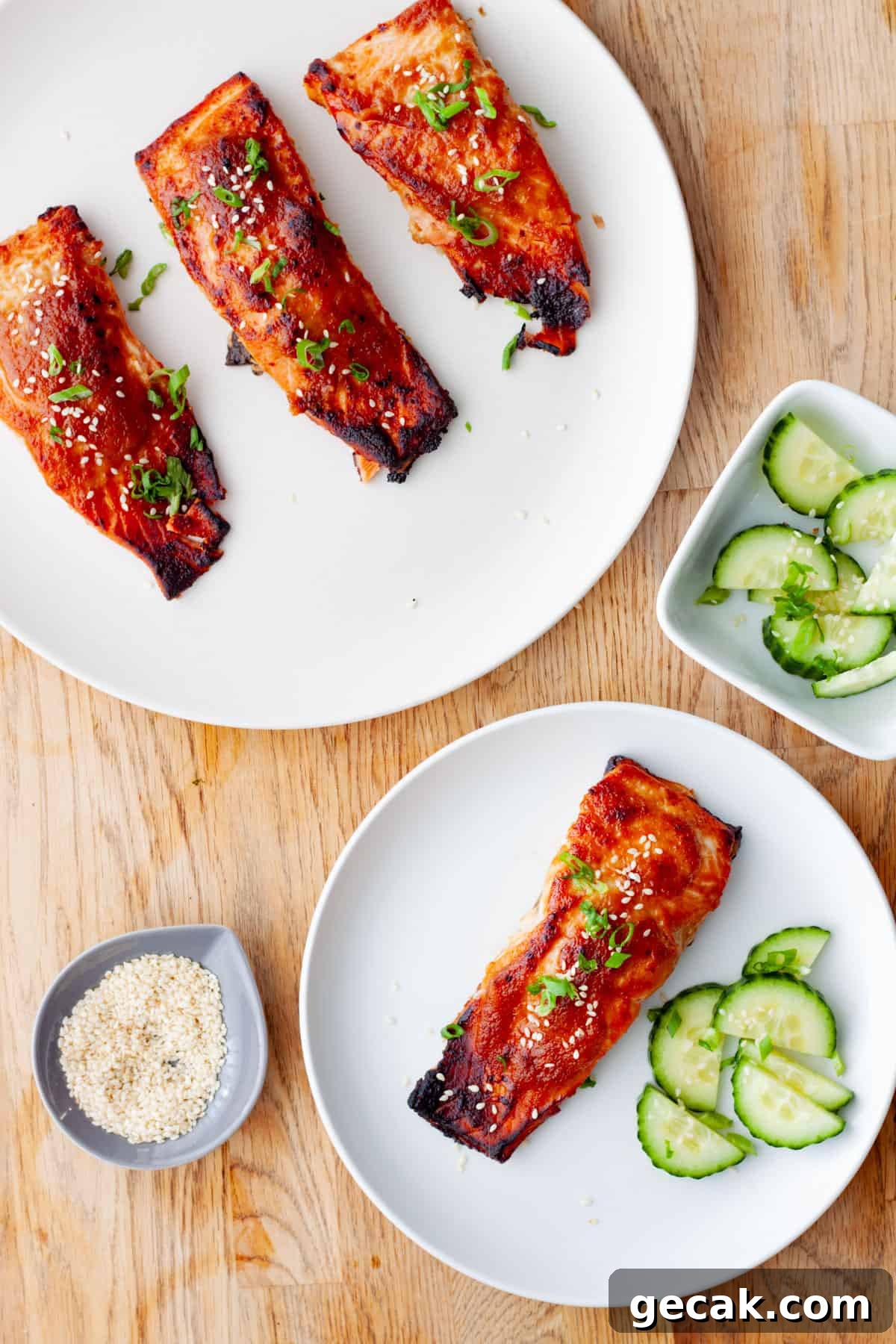 A platter of miso salmon with a serving of salmon on a small plate with cucumbers and sesame seeds.