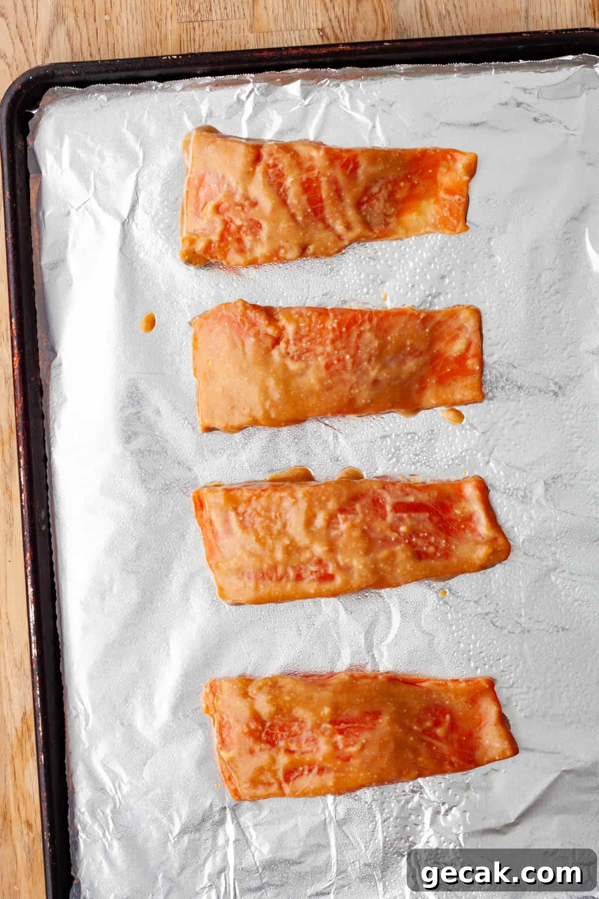 A baking sheet covered in aluminum foil with miso marinated salmon ready to get roasted.