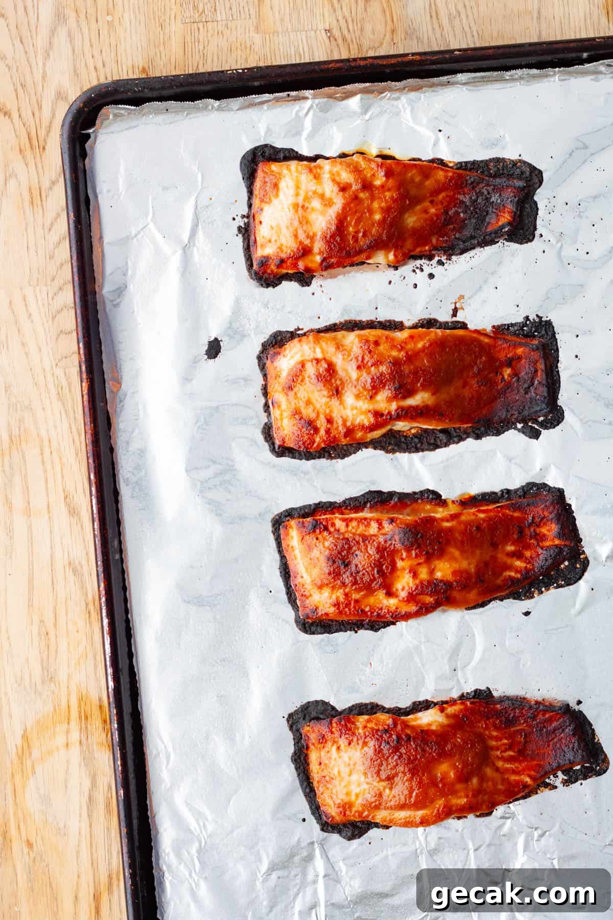 Portions of roasted and broiled miso salmon on a foil lined baking sheet.