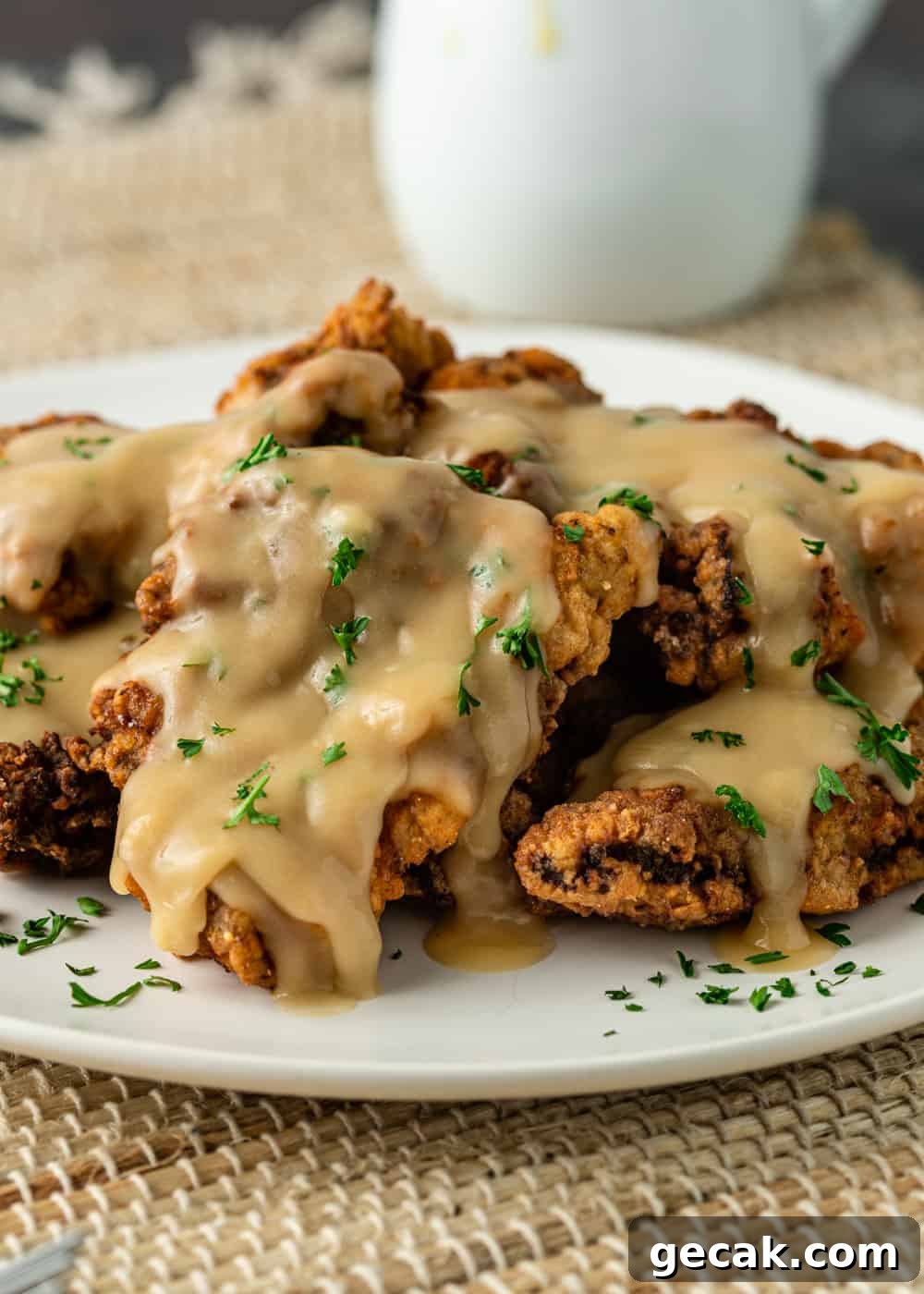 plate of chicken fried steaks stacked with gravy poured over