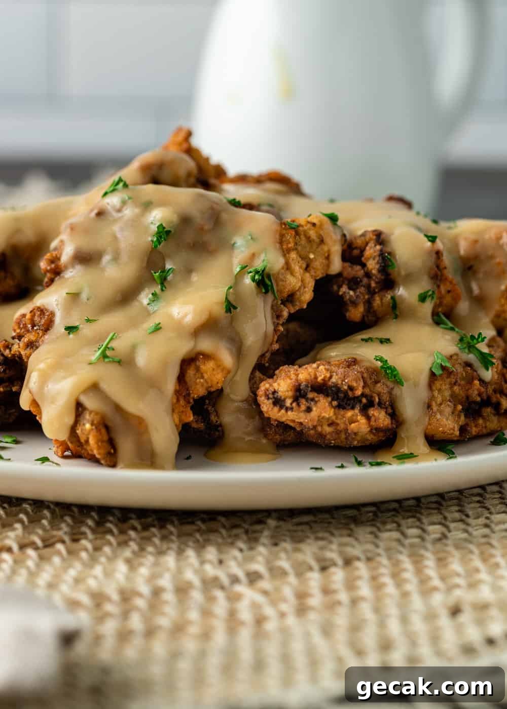 plate of fried cube steak covered with gravy and chopped parsley